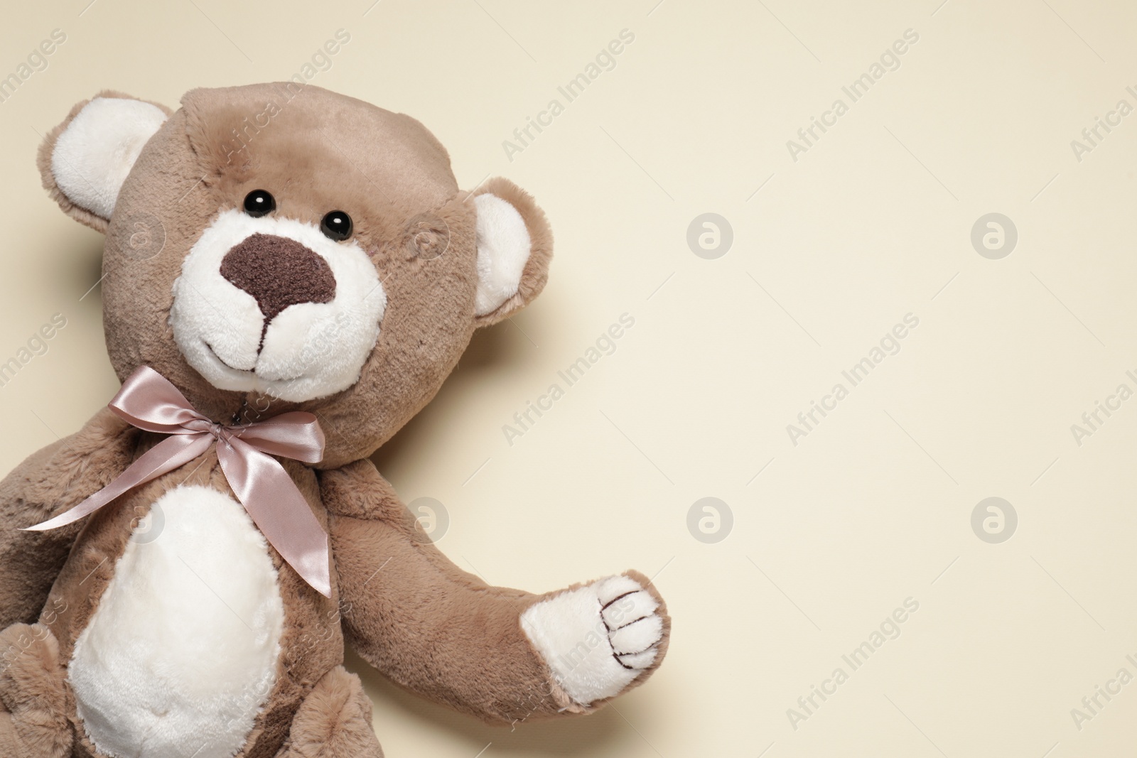 Photo of Cute teddy bear on beige background, top view. Space for text