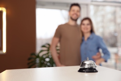 Photo of Hotel service bell on reception desk and blurred young couple on background