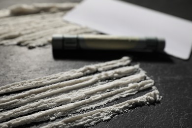 Photo of Drug addiction. Cocaine and rolled dollar banknote on dark textured table, closeup