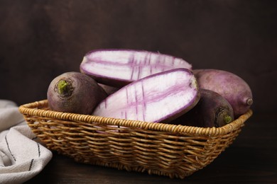 Photo of Purple daikon radishes in wicker basket on wooden table