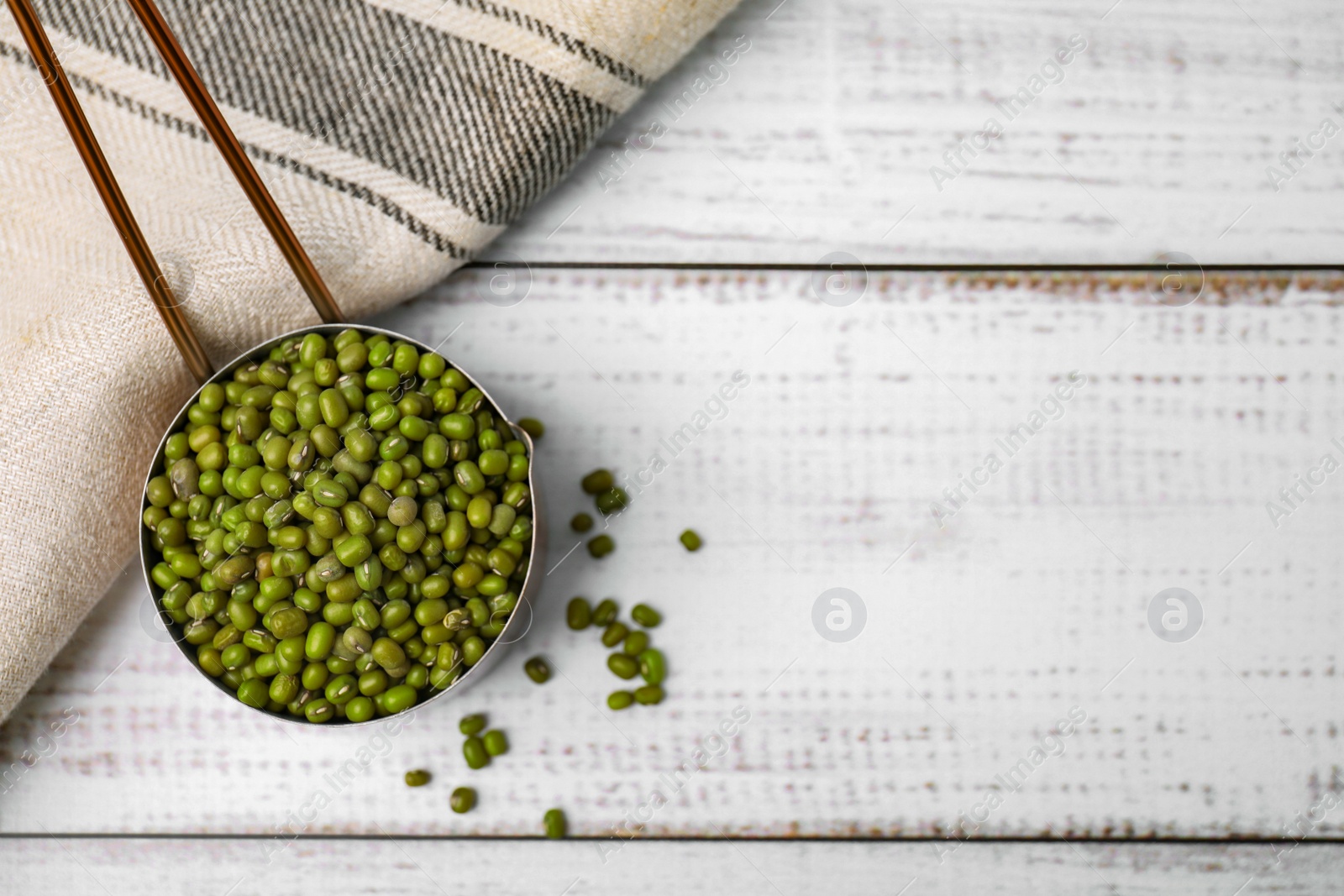 Photo of Scoop with mung beans on white wooden table, flat lay. Space for text