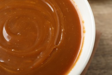 Photo of Yummy salted caramel in bowl on table, closeup