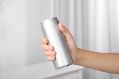 Woman holding aluminum can with beverage on blurred background, closeup. Space for design