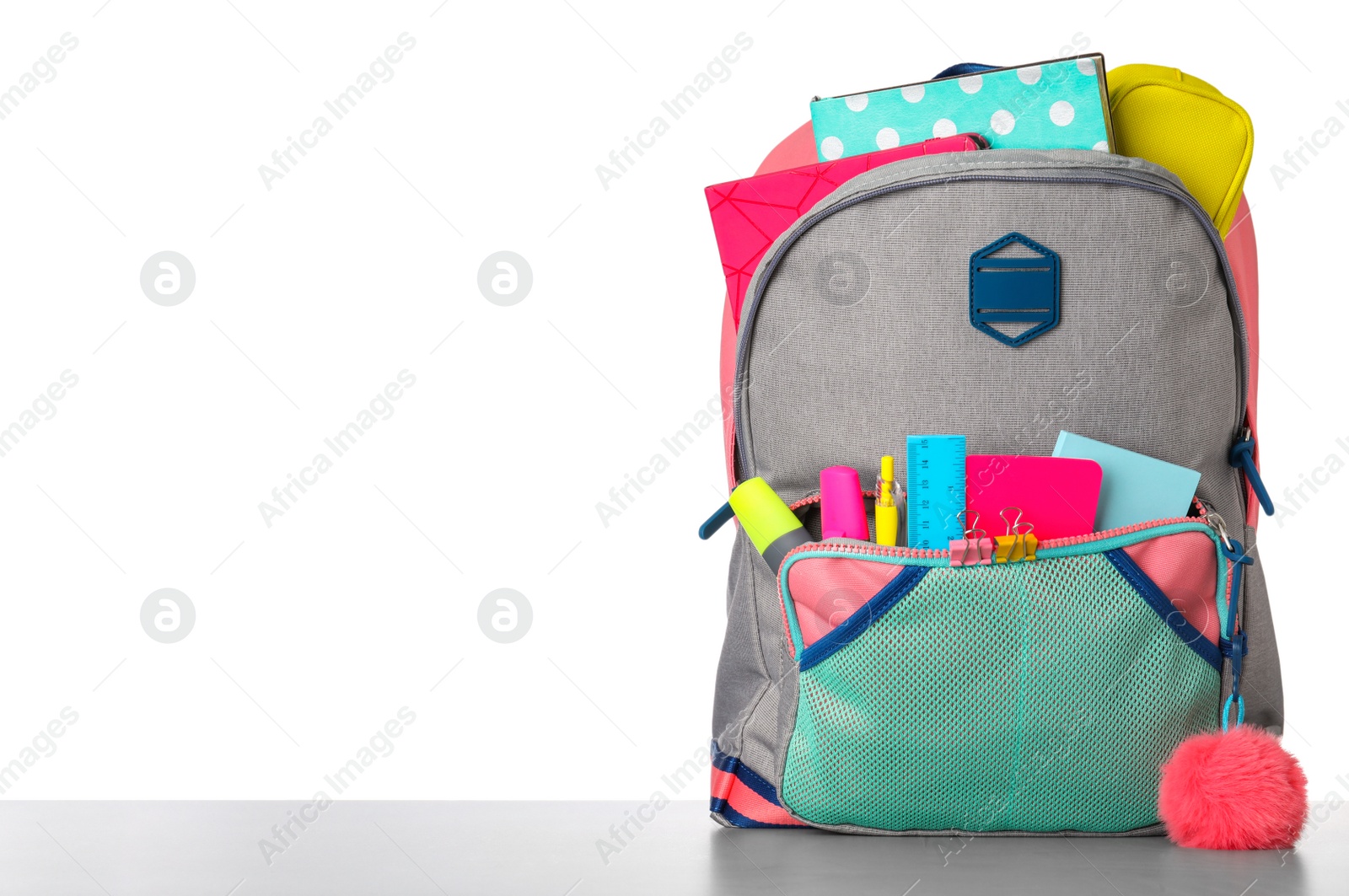 Photo of Bright backpack with school stationery on grey stone table against white background