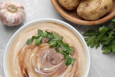 Photo of Delicious cream soup with soy sauce and parsley on light grey marble table, flat lay