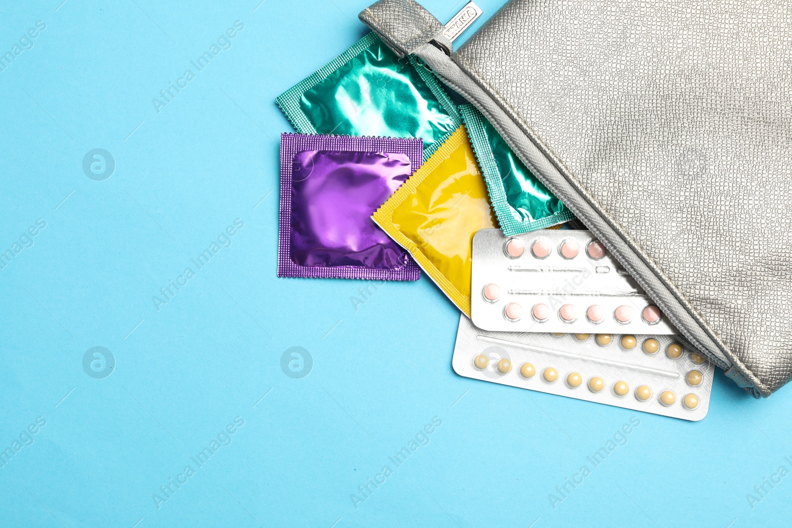 Photo of Flat lay composition with birth control pills and condoms on light blue background. Safe sex concept