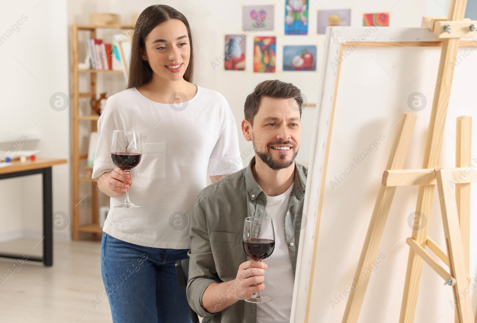 Photo of Artist and her student with glasses of wine having painting class in studio. Creative hobby