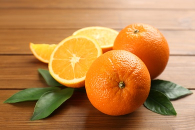 Whole and cut delicious ripe oranges on wooden table