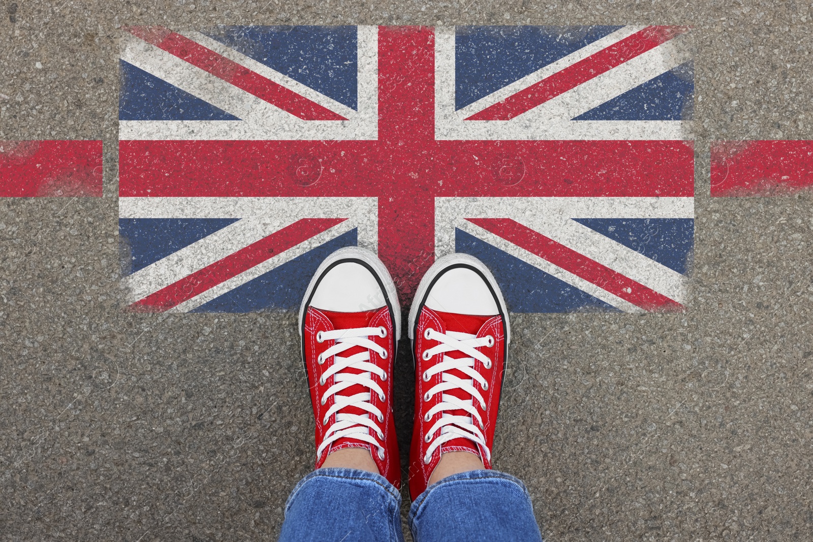 Image of Immigration. Woman standing on asphalt near flag of United Kingdom, top view