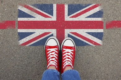 Image of Immigration. Woman standing on asphalt near flag of United Kingdom, top view