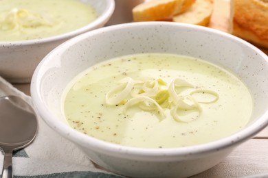 Photo of Bowl of tasty leek soup on table, closeup