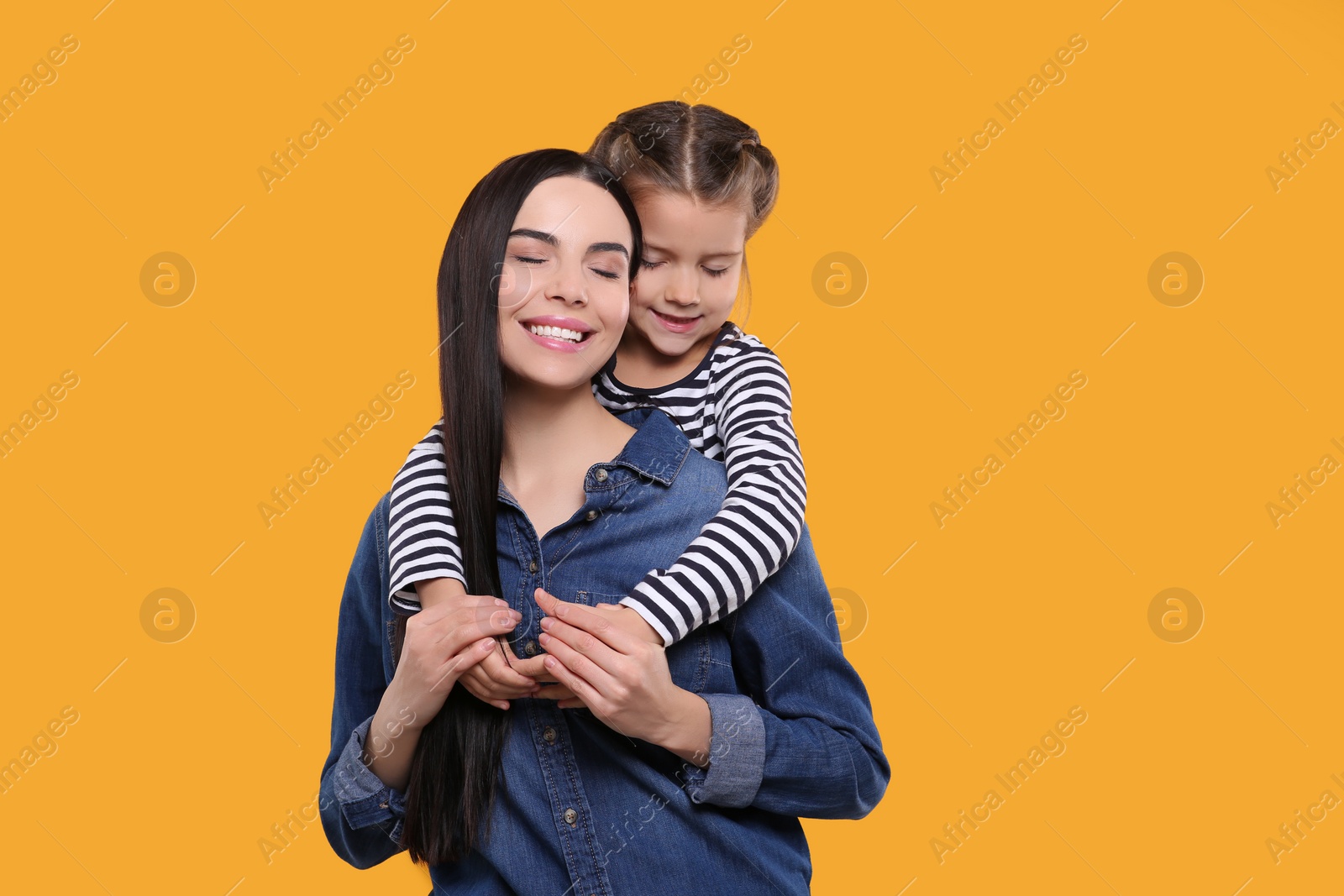 Photo of Happy woman with her cute daughter on yellow background, space for text. Mother's day celebration