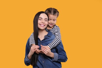 Happy woman with her cute daughter on yellow background, space for text. Mother's day celebration