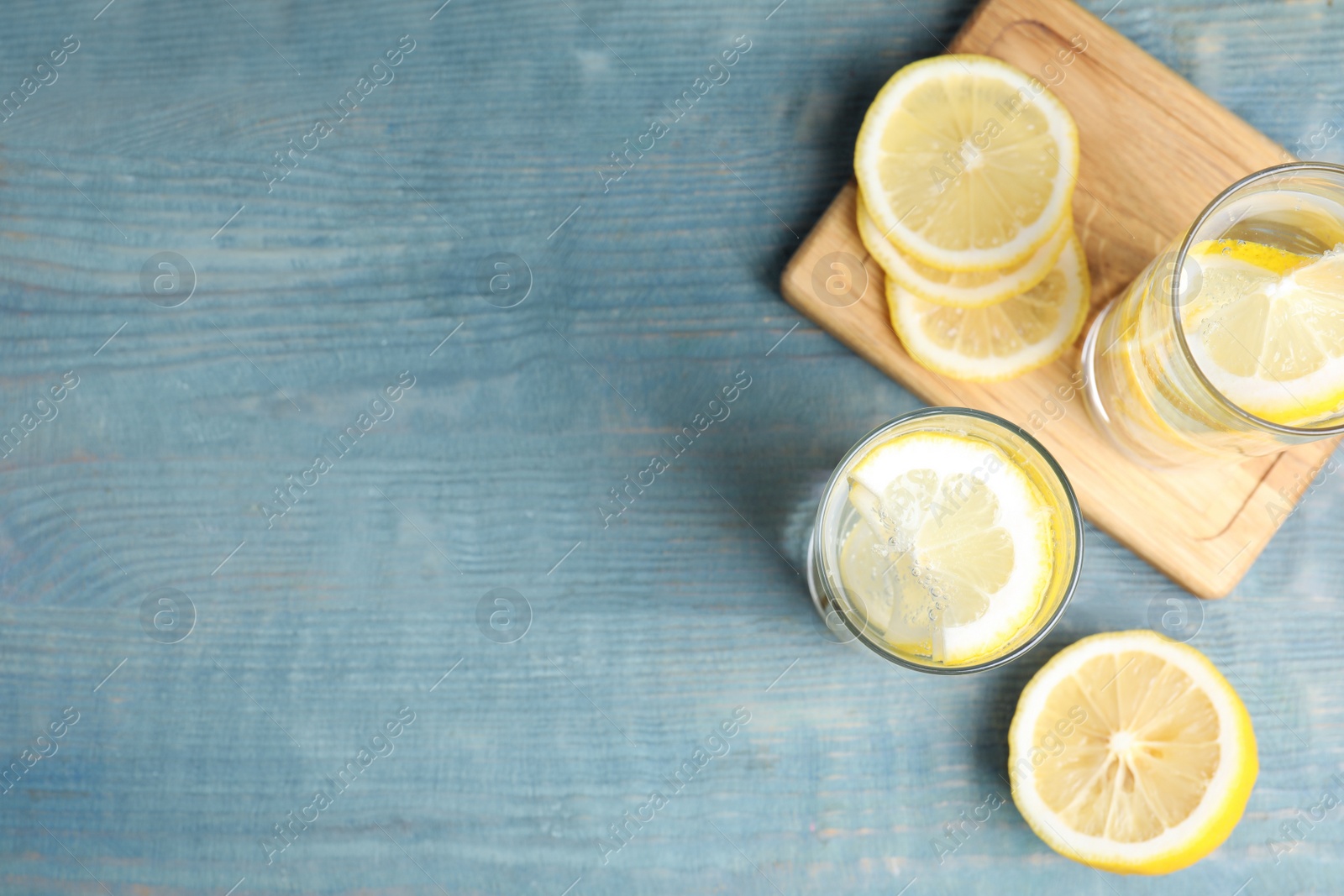 Photo of Soda water with lemon slices on blue wooden table, flat lay. Space for text