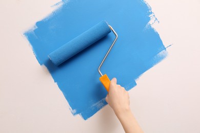 Photo of Woman painting wall with roller, closeup. Redecoration