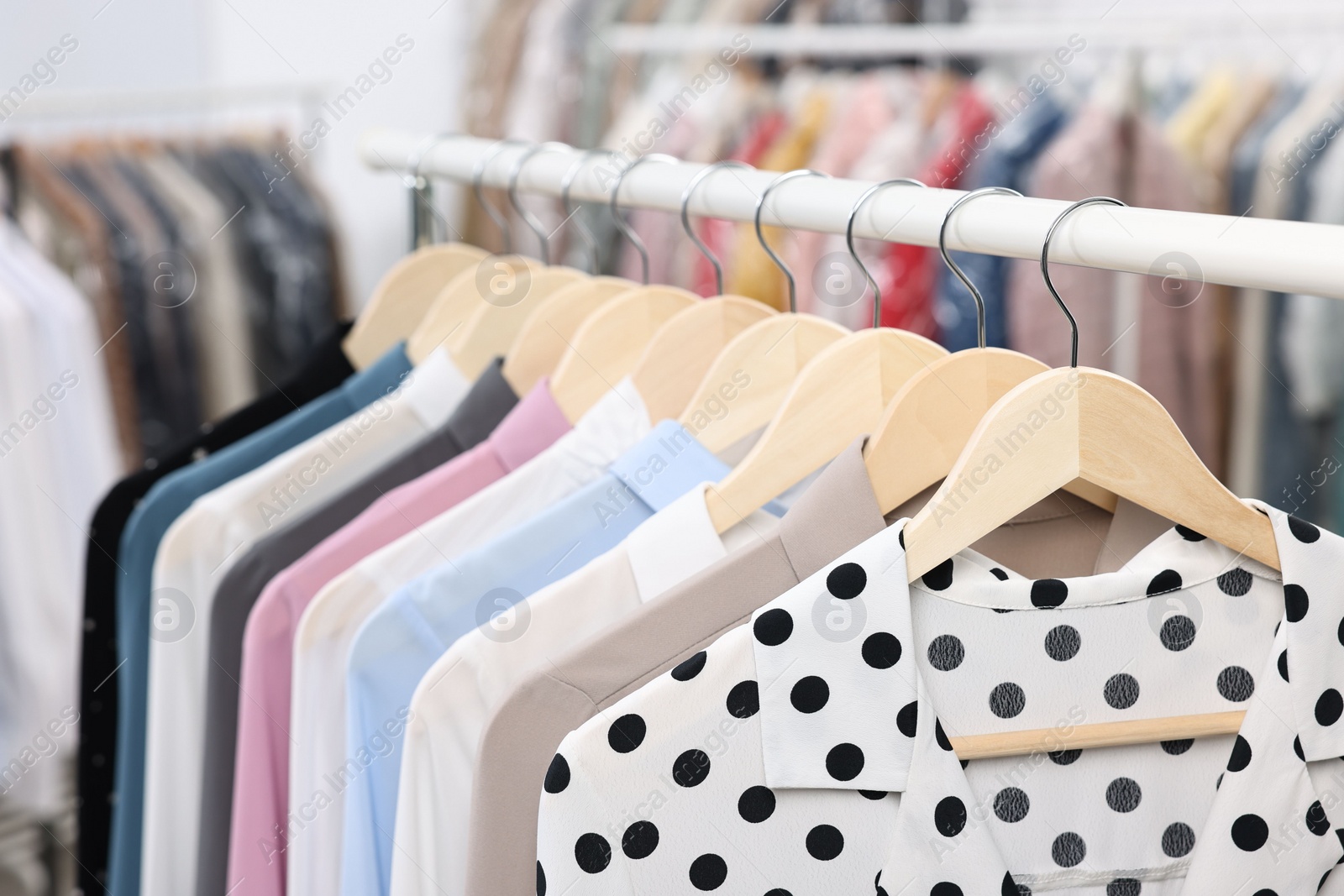 Photo of Dry-cleaning service. Many different clothes hanging on rack indoors, closeup