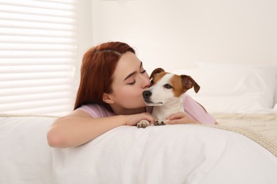 Photo of Woman kissing cute Jack Russell Terrier dog on bed at home