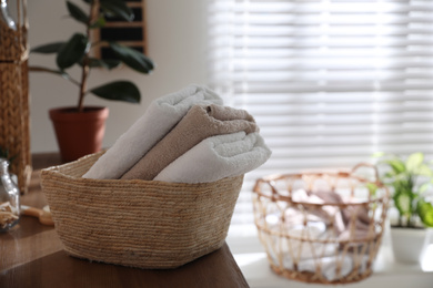 Photo of Basket with fresh towels on shelf indoors. Bathroom interior element