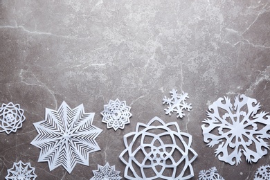 Flat lay composition with paper snowflakes on marble background, space for text. Winter season