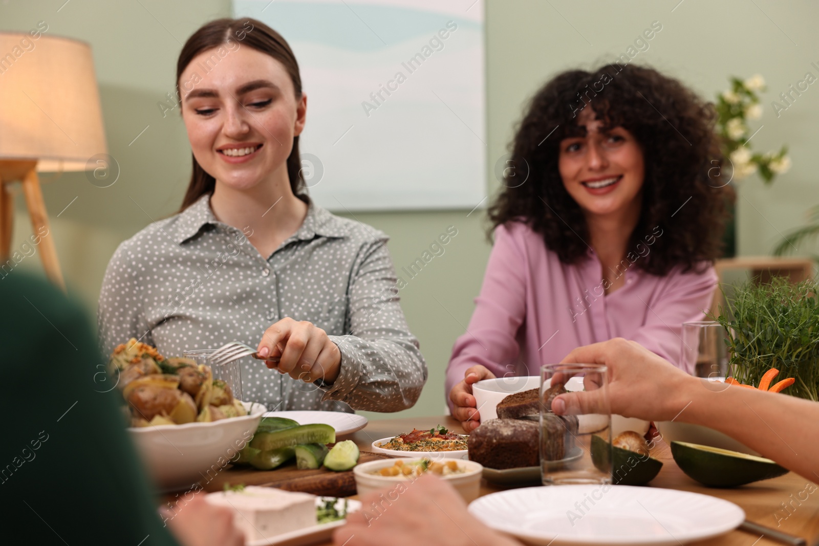 Photo of Friends eating vegetarian food at table indoors