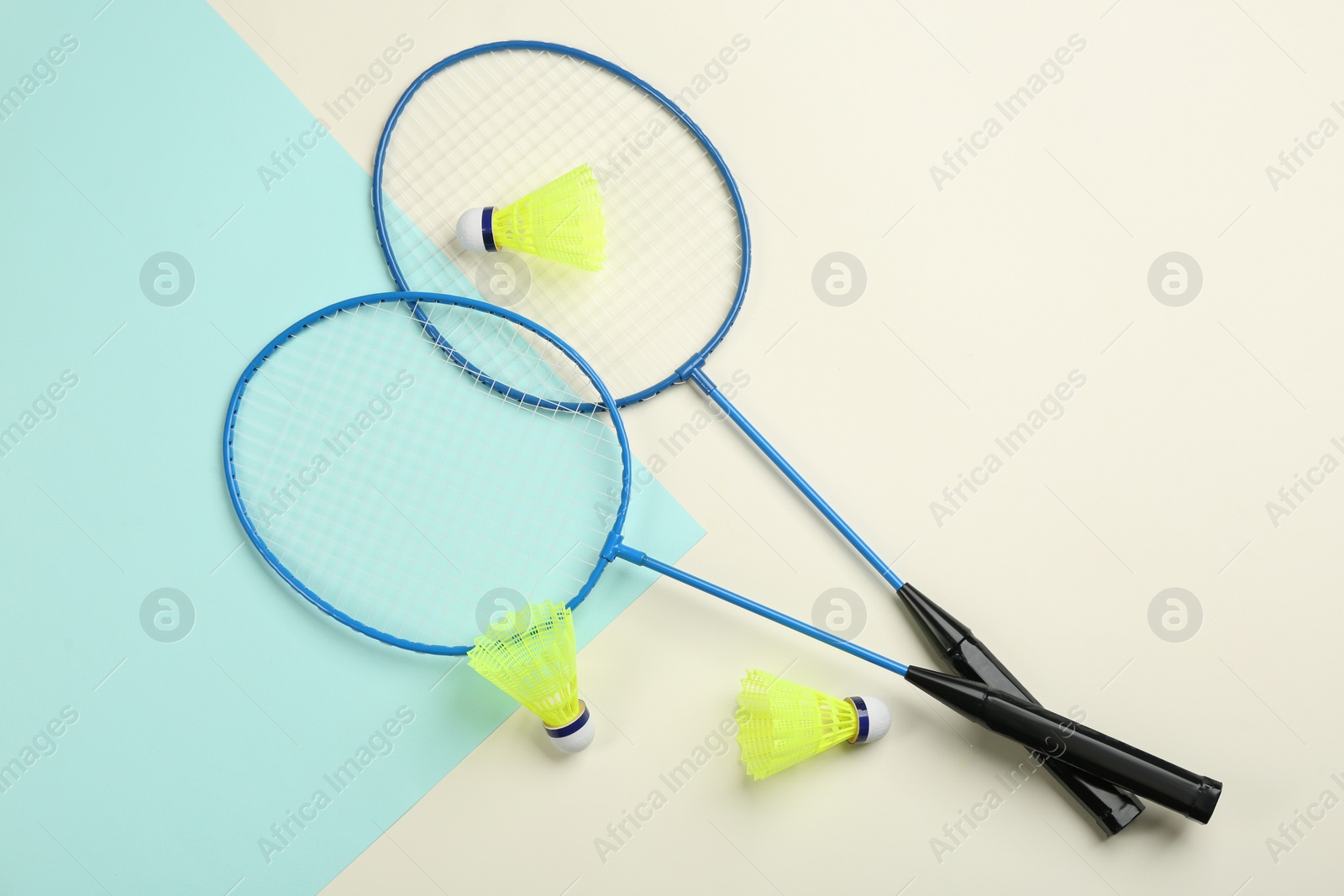 Photo of Rackets and shuttlecocks on color background, flat lay. Badminton equipment