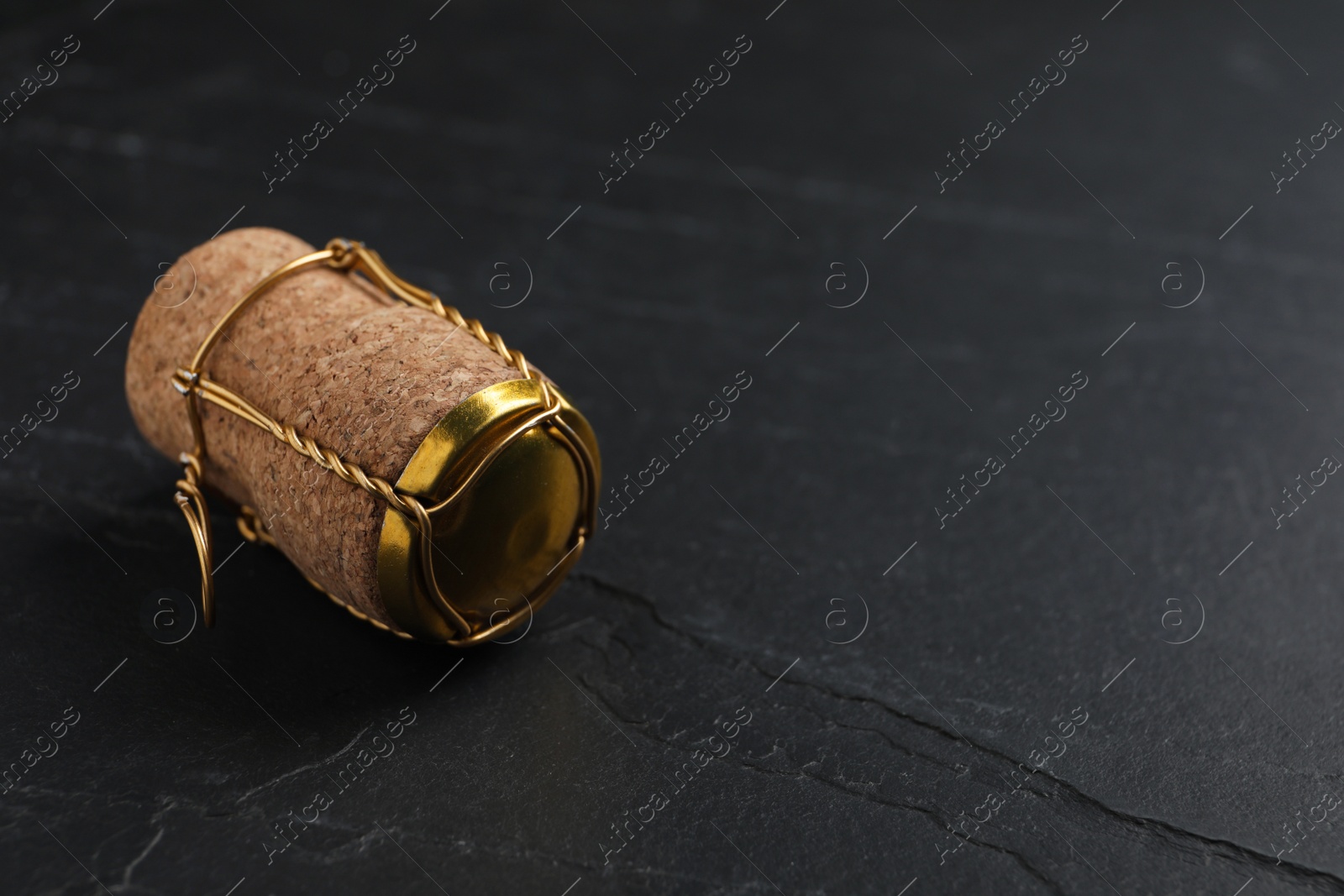 Photo of Cork of sparkling wine and muselet cap on black table. Space for text