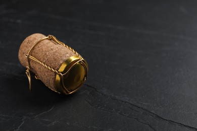 Photo of Cork of sparkling wine and muselet cap on black table. Space for text