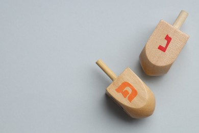 Photo of Wooden dreidels on grey background, flat lay with space for text. Traditional Hanukkah game