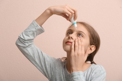 Conjunctivitis. Girl using eye drops on beige background