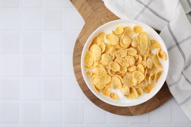 Photo of Breakfast cereal. Tasty corn flakes with milk in bowl on white tiled table, top view. Space for text