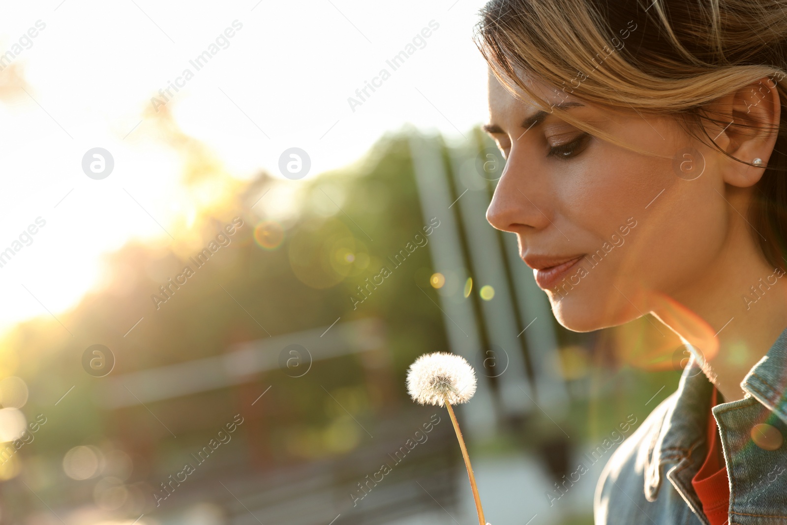 Photo of Young woman with dandelion in park on sunny day. Allergy free concept