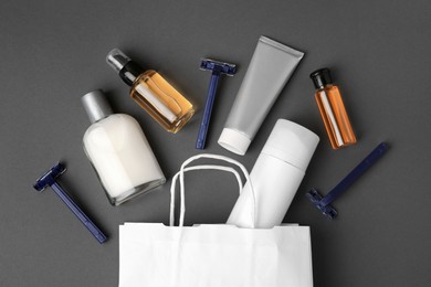 Photo of Different men's shaving accessories and paper bag on dark grey background, flat lay