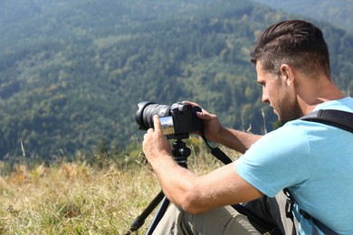 Photo of Man taking photo of nature with modern camera on tripod outdoors