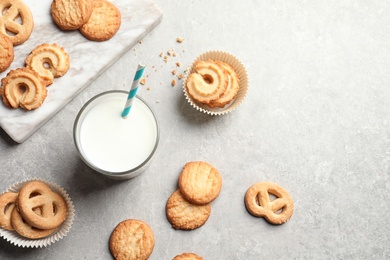 Flat lay composition with Danish butter cookies and glass of milk on grey background, space for text