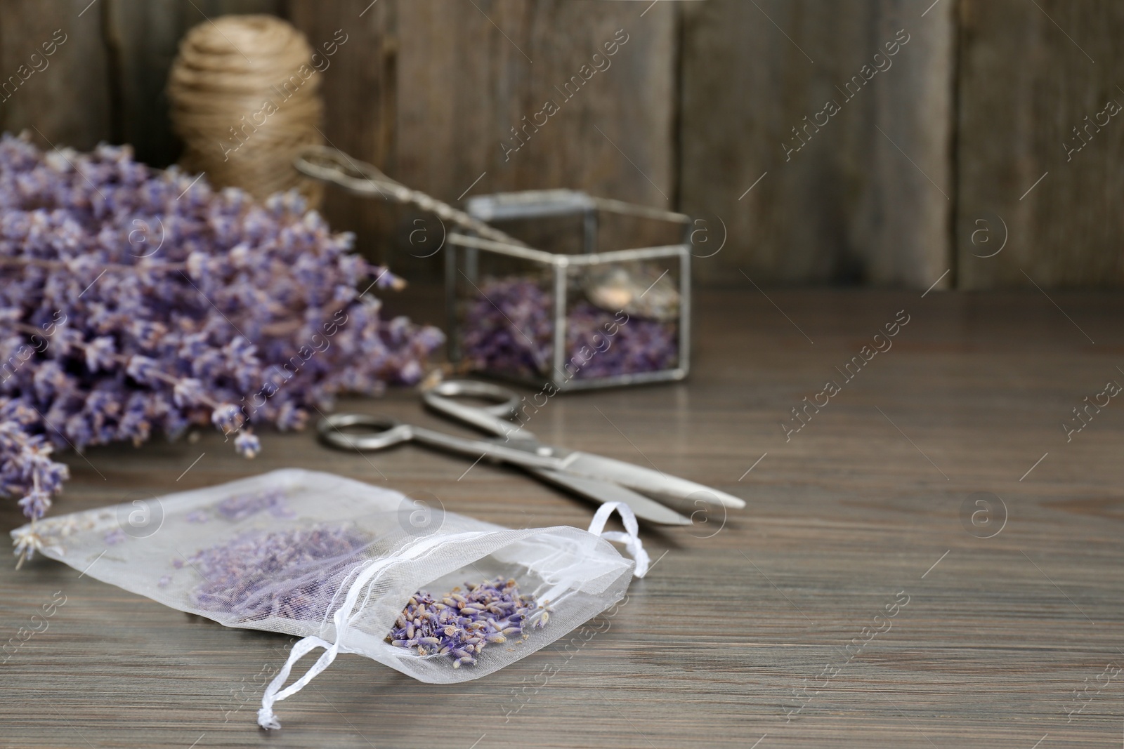 Photo of Scented sachet with dried lavender flowers on wooden table, space for text
