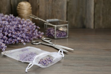 Scented sachet with dried lavender flowers on wooden table, space for text