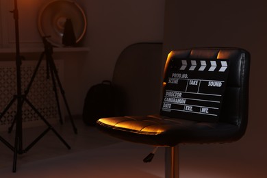 Photo of Casting call. Chair, clapperboard and different equipment in modern studio, space for text