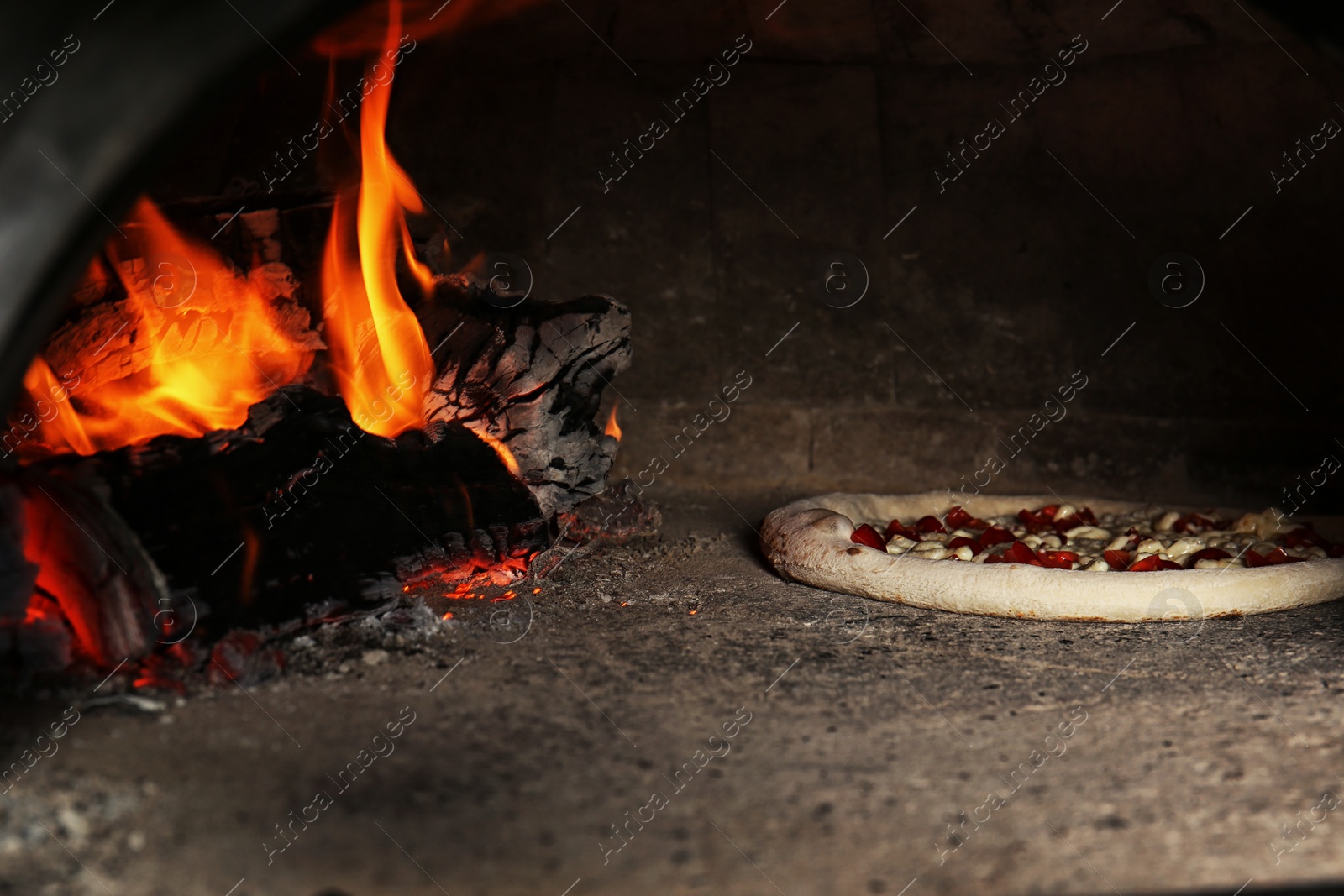 Photo of Oven with burning firewood and tasty pizza in restaurant kitchen