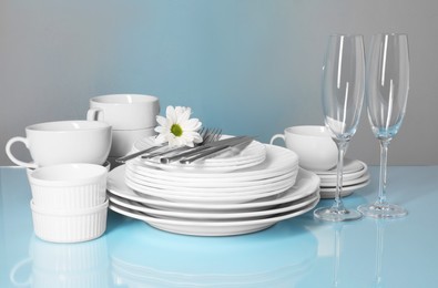 Set of clean dishes, glasses and cutlery on light blue table