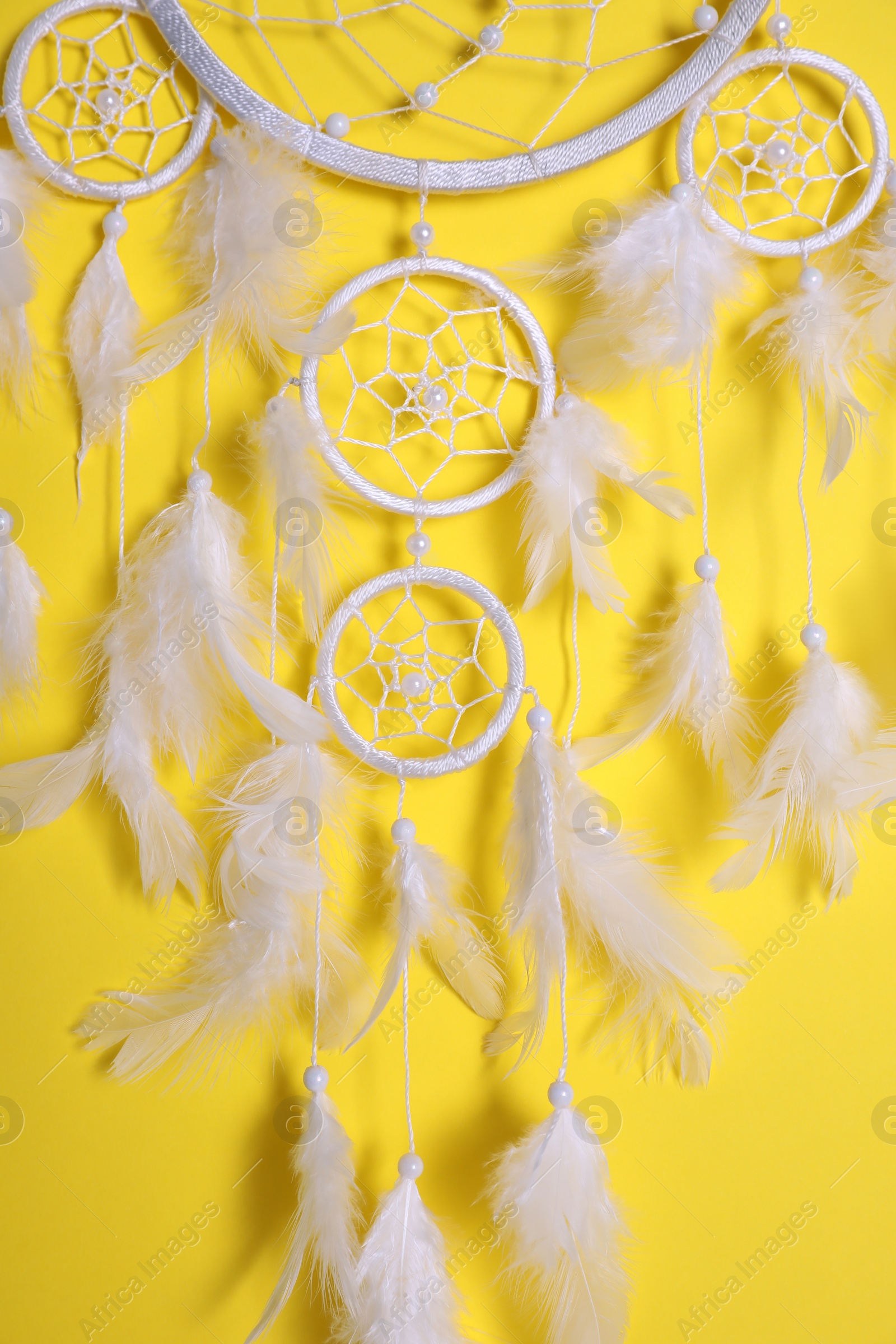 Photo of Beautiful dream catcher hanging on yellow background