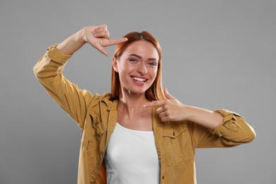 Photo of Casting call. Young woman showing frame gesture on grey background