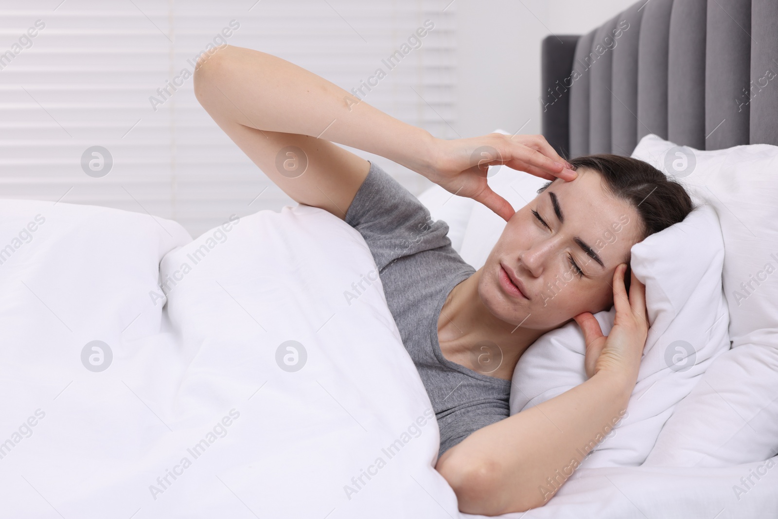 Photo of Sad woman suffering from headache in bed indoors