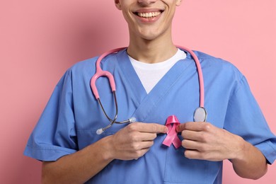 Photo of Mammologist with pink ribbon on color background, closeup. Breast cancer awareness