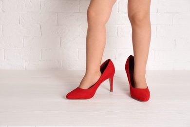 Photo of Little girl in oversized shoes near brick wall with space for text, closeup on legs