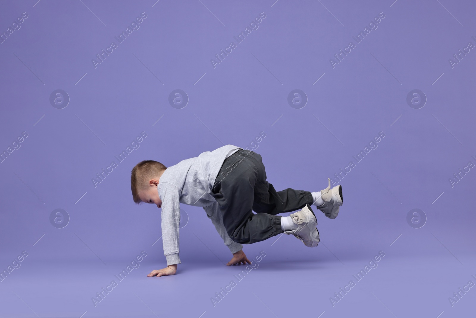 Photo of Happy little boy dancing on violet background