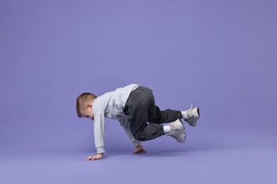 Happy little boy dancing on violet background