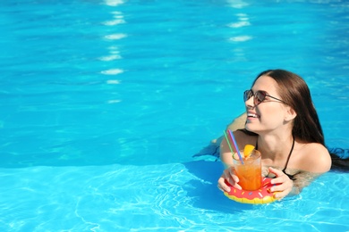 Beautiful young woman with cocktail wearing bikini in swimming pool