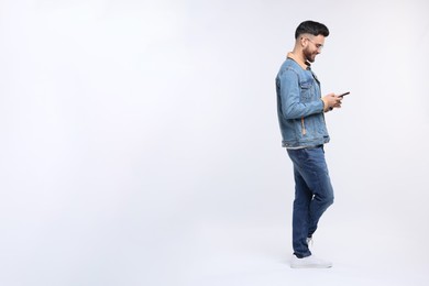 Handsome man using smartphone on white background, space for text