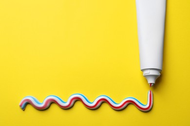 Photo of Blank tube with squeezed out toothpaste on yellow background, flat lay. Space for text