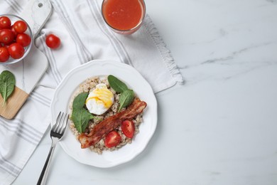Delicious boiled oatmeal with poached egg, bacon and tomato served on white marble table, flat lay. Space for text